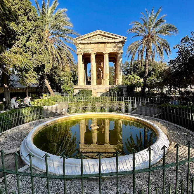 A temple-like structure with palm trees and a fountain in the Lower Barrakka Gardens.