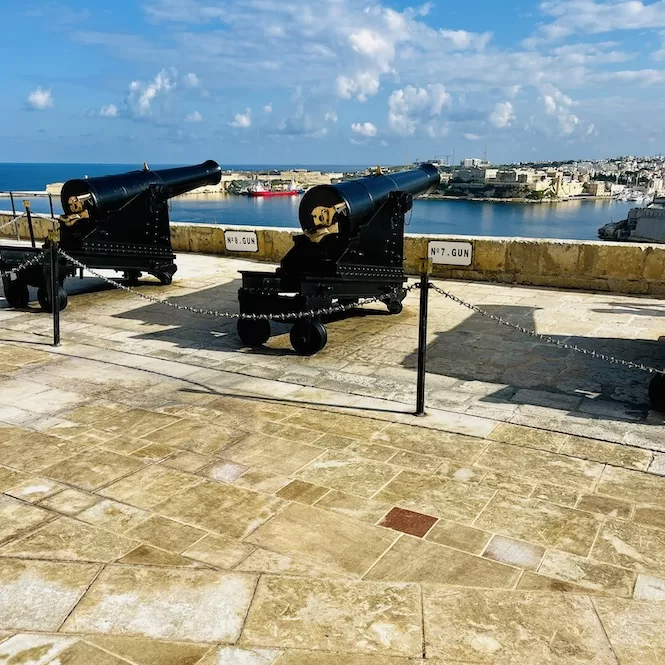 Saluting Battery cannons on a fort below the Upper Barrakka Gardens overlooking the sea on a sunny day.