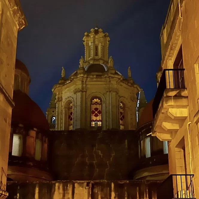 An illuminated Church of Sacro Cuor with intricate architectural details against the dark night sky. The church is located in Sliema, Malta.