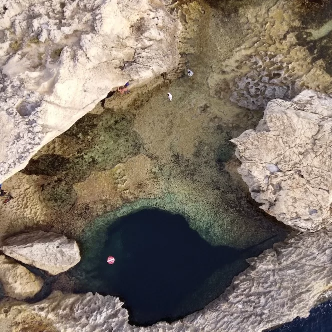 Aerial view of the famous Blue Hole, a renowned snorkelling spot in Gozo, surrounded by rocky cliffs.