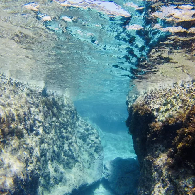 Underwater passages through rocky formations are seen while snorkelling in Malta.