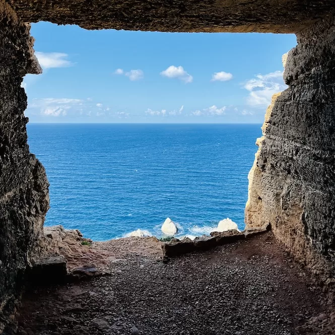 A breathtaking view from a rock-cut observation post in Majjistral Park, framing the deep blue sea against the rugged coastal cliffs.