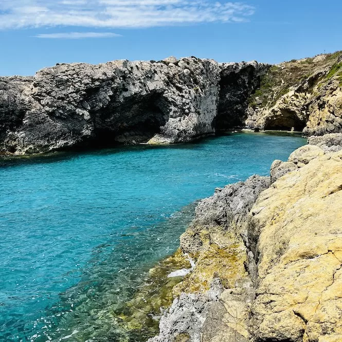 Rocky coastline leading to the serene waters of Ta' Bumbarin Bay, a short walk away from Hondoq Bay in Gozo, Malta.