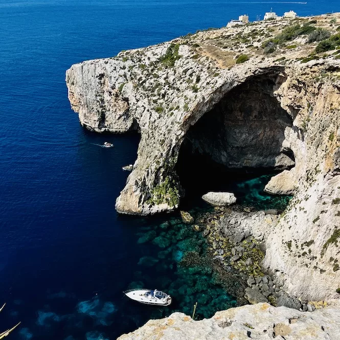 A boat is anchored near Blue Grotto in Malta, known for its captivating limestone caves and blue waters of the Mediterranean Sea.