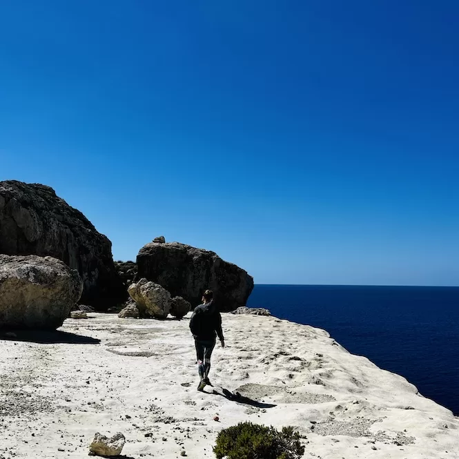 A person hiking along the rugged coastline of Malta, enjoying the scenic views of the endless blue sea.