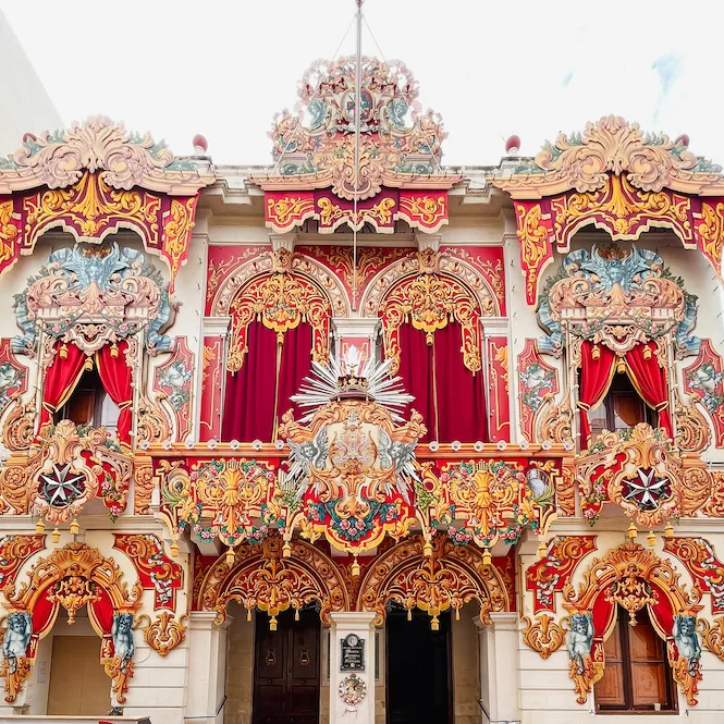 Elaborate traditional feast decorations adorning a building facade in Naxxar, Malta, showcasing intricate designs and vibrant colours typical of Maltese celebrations.