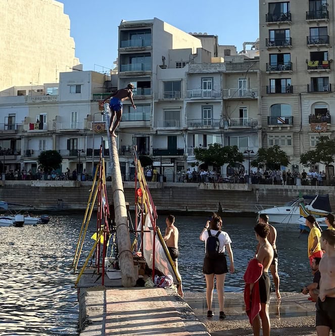 Participant balancing on the slippery pole during the ġostra at the St Julian’s feast, held on the last Sunday of August in Malta.