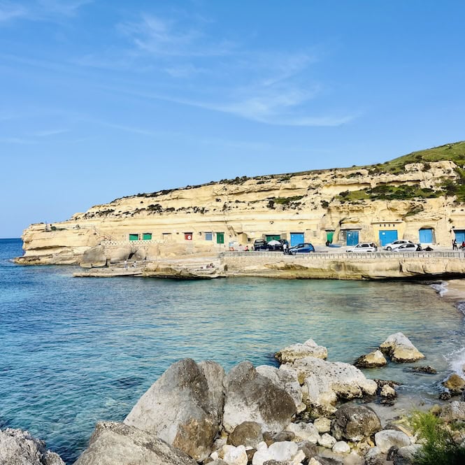 Boathouses with bright blue doors at Daħlet Qorrot Bay in Gozo.