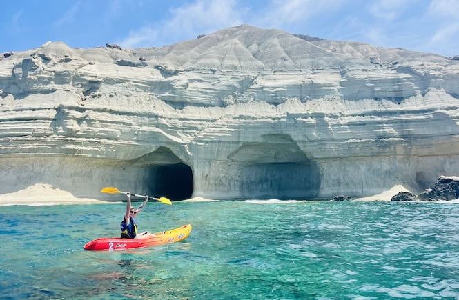 A kayaker paddles towards the entrance of Ta' Marija Cave, a popular kayaking destination near Gnejna Beach in Malta.