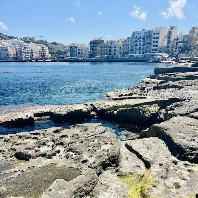 Rocky coastline with apartment buildings along Marsalforn bay in Gozo, Malta