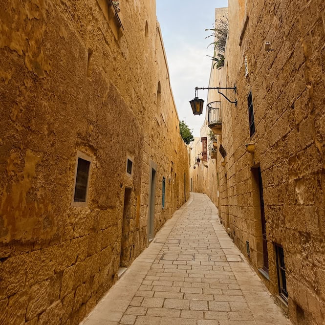 A charming narrow stone street in Malta, showcasing the island's historic architecture, great to explore in September.