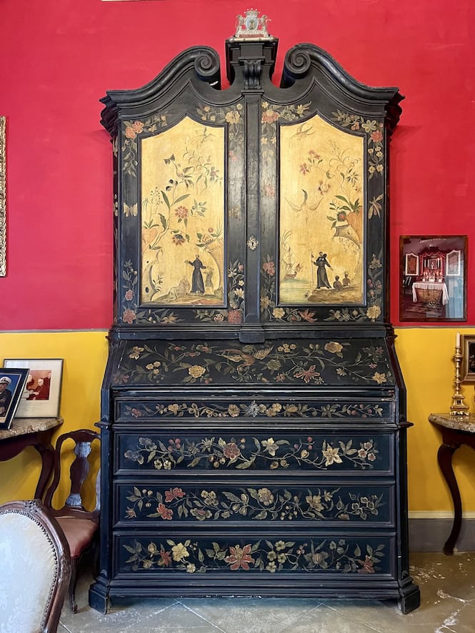 Ornate 18th-century portable chapel with black lacquer finish and gold floral designs, featuring painted religious scenes on its doors, displayed in the Sala Grande of Casa Rocca Piccola.