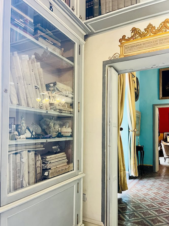Room with white cabinets and bookshelves filled with documents and books. A doorway leads to another room with blue walls.