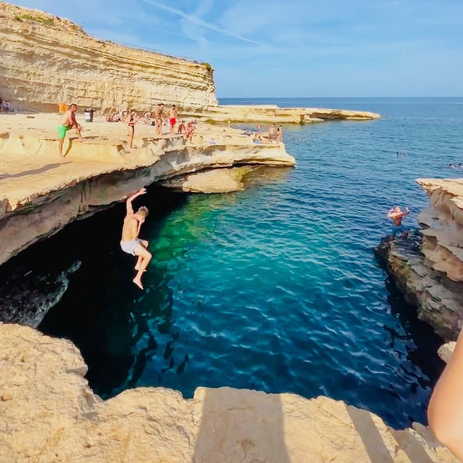 St. Peter's Pool, Malta, features a stunning natural swimming pool with clear turquoise waters surrounded by rugged rock formations. This popular tourist attraction offers a great spot for cliff diving.