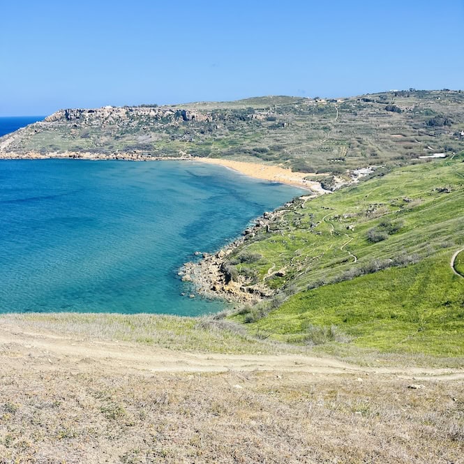 anoramic view of Ramla Bay, Gozo, Malta, with its distinctive red sand beach and green hills, taken during the early spring month of March.