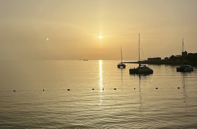 Golden sunset over calm waters with sailboats in Malta – a peaceful scene that captures one of the most romantic things to do in Malta for couples.