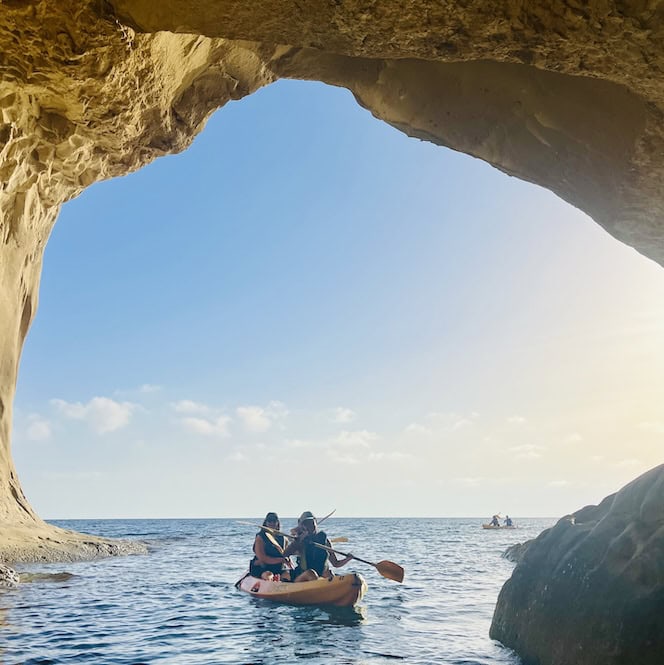 Couple kayaking through the Ta’ Marija sea cave near Gnejna Bay, Malta – a peaceful and adventurous experience among the most romantic things to do in Malta.