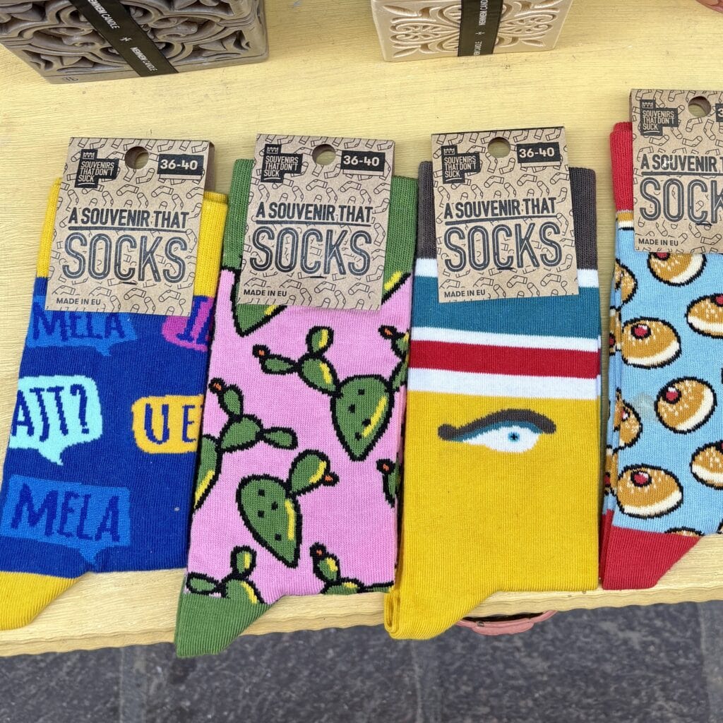 Colorful socks featuring Maltese cultural icons like prickly pear, honey rings, and local phrases, part of modern Maltese souvenirs collection